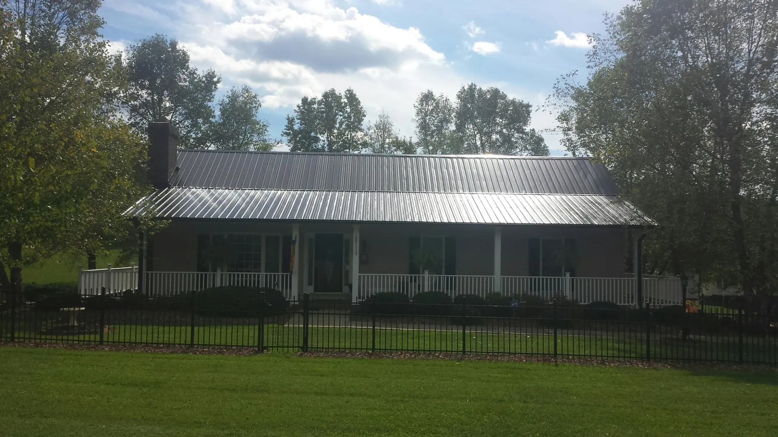 Gray metal roof on a brick ranch with a full width front porch — Gutter Guard Installation work by our crew in Howard